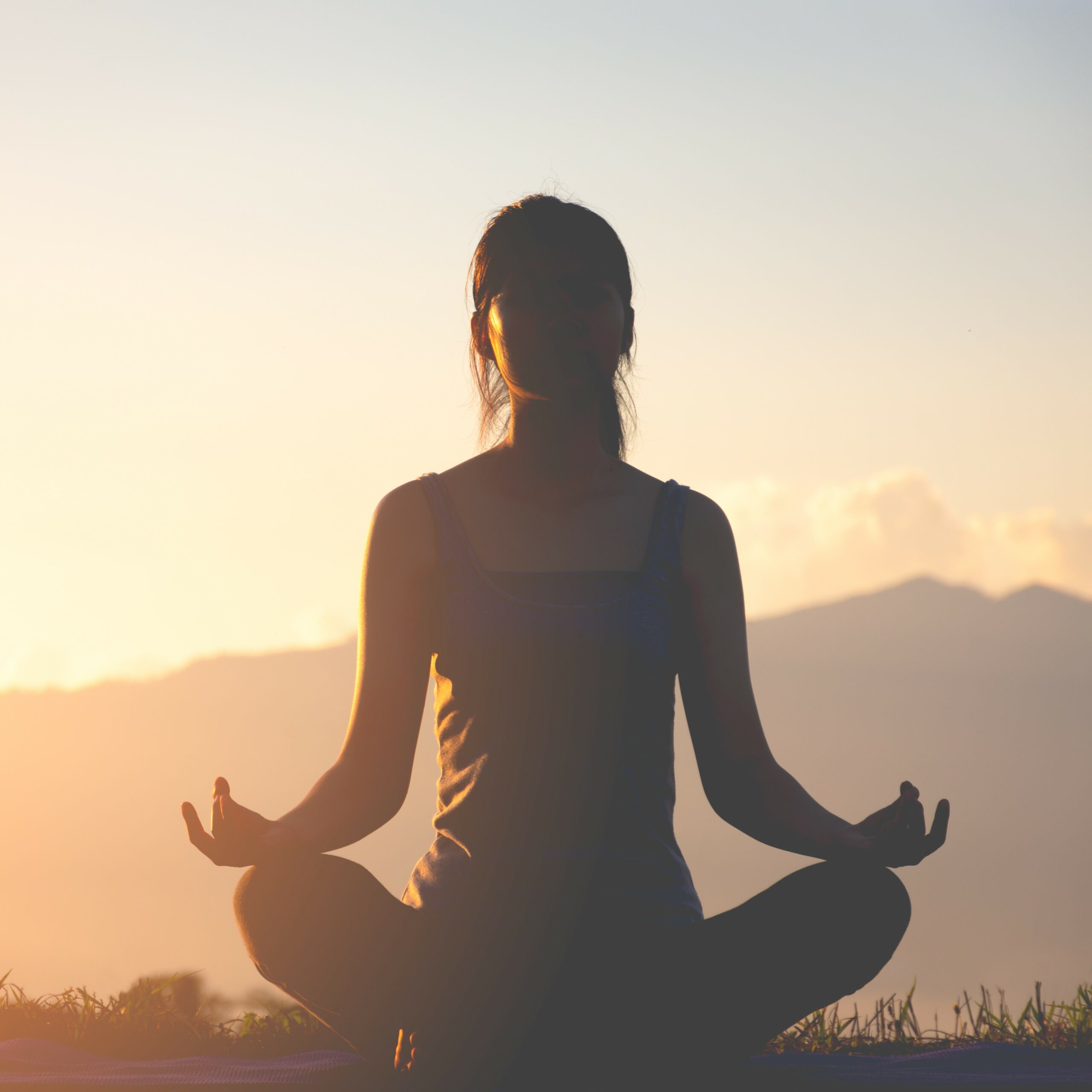 silhouette fitness girl practicing yoga on mountain with sun light